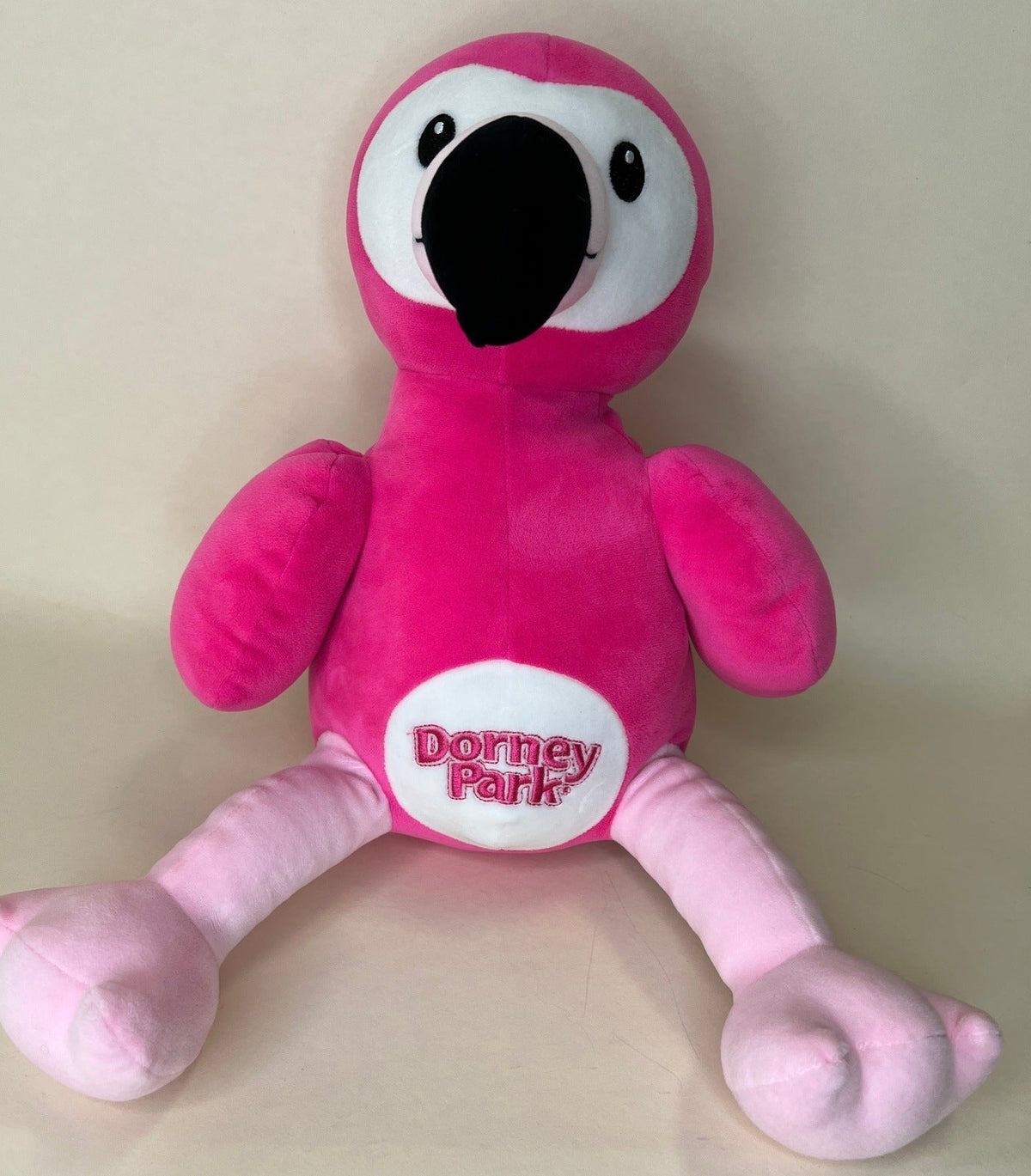 Pink plush flamingo pet toy with large black eye and “Dorney Park” badge
