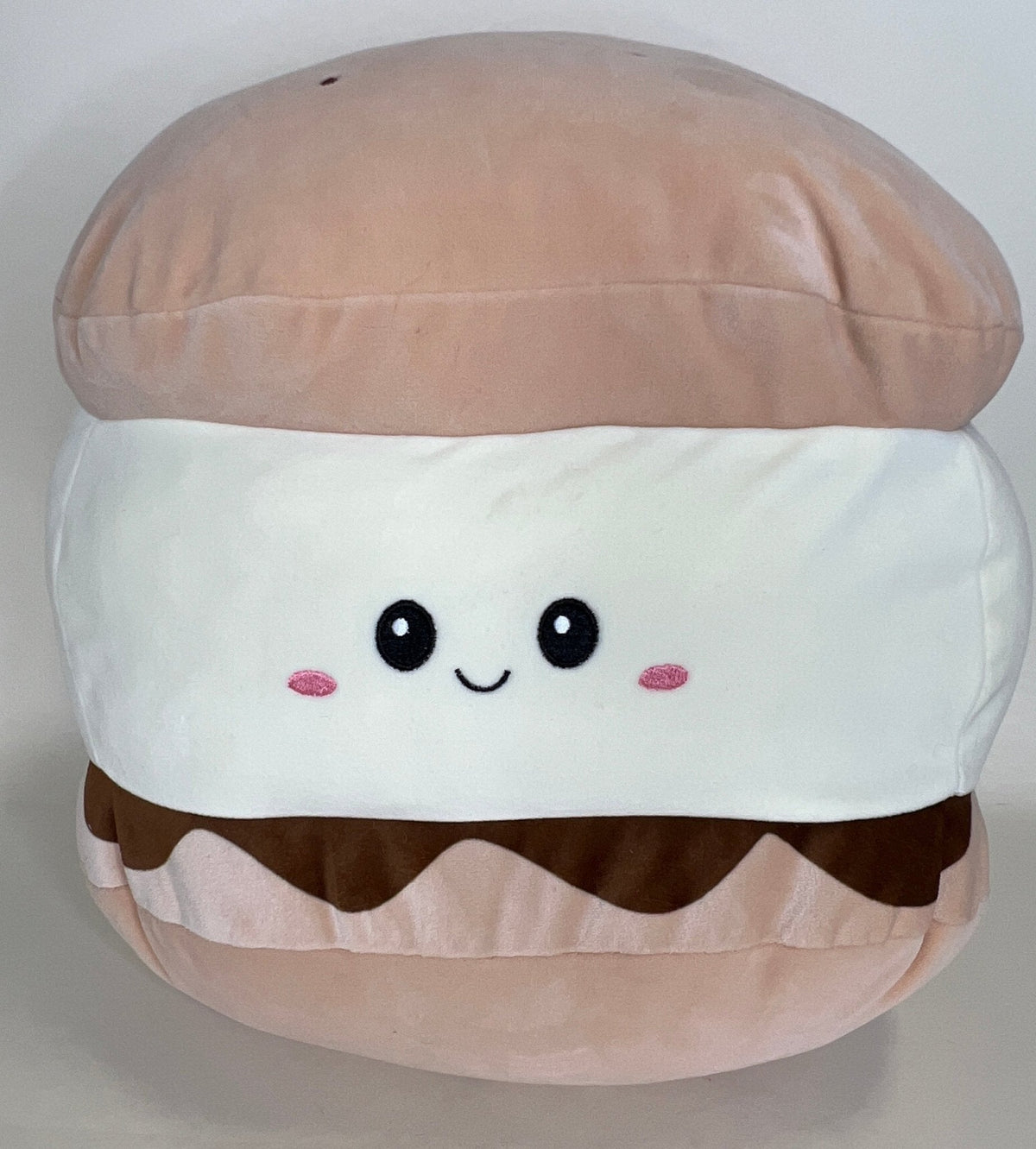 Layered bun-shaped plush cuddler with smiling face, pink cheeks, and brown wave detail