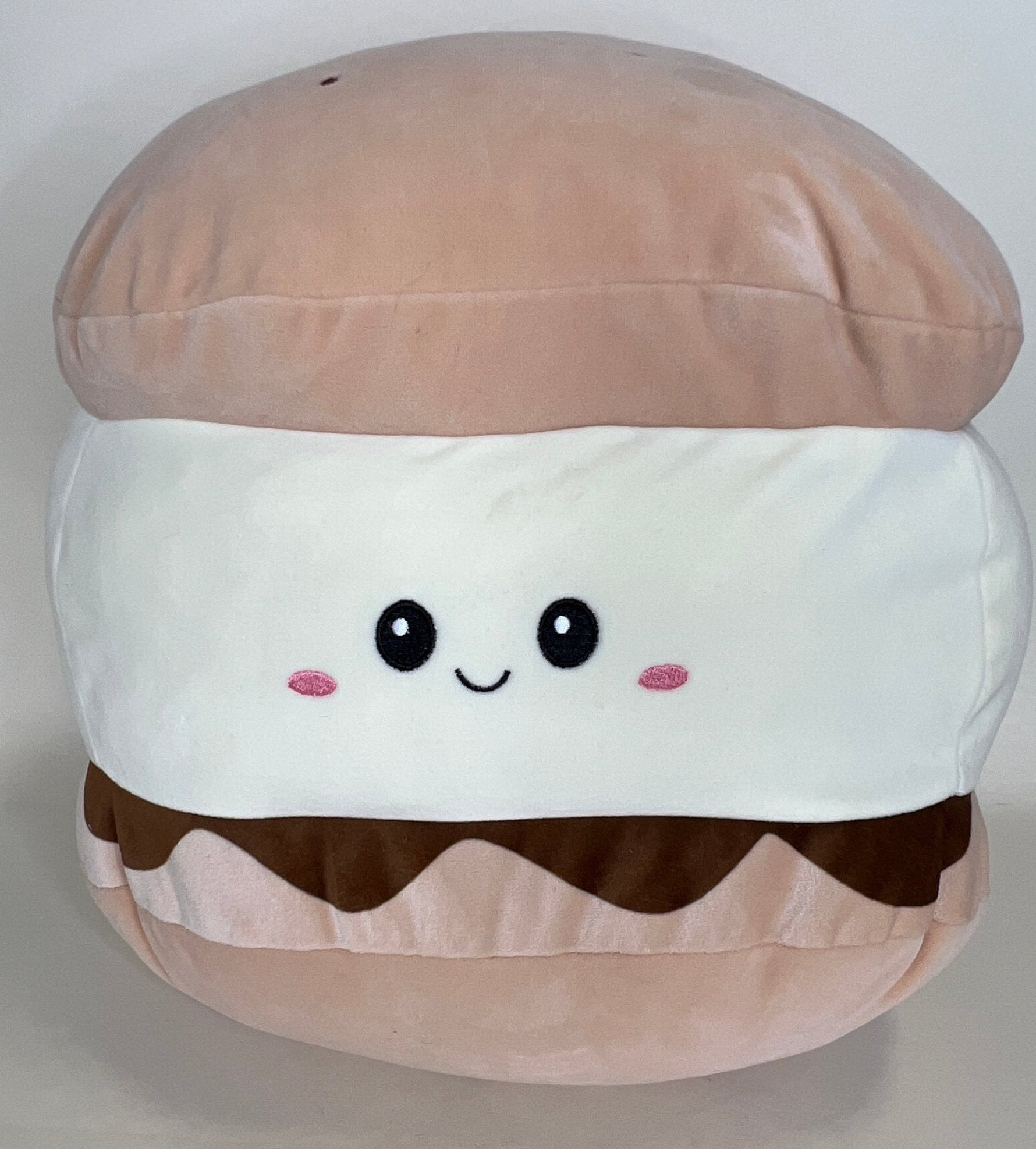 Layered bun-shaped plush cuddler with smiling face, pink cheeks, and brown wave detail
