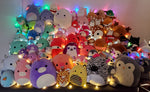 Assorted plush squishy animal toys with glowing LED lights in a packed row