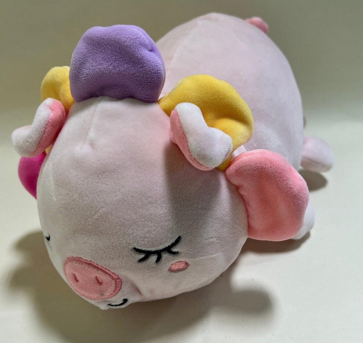 Back view of pastel pig plush squishy pet toy with multicolor tuft and curled tail