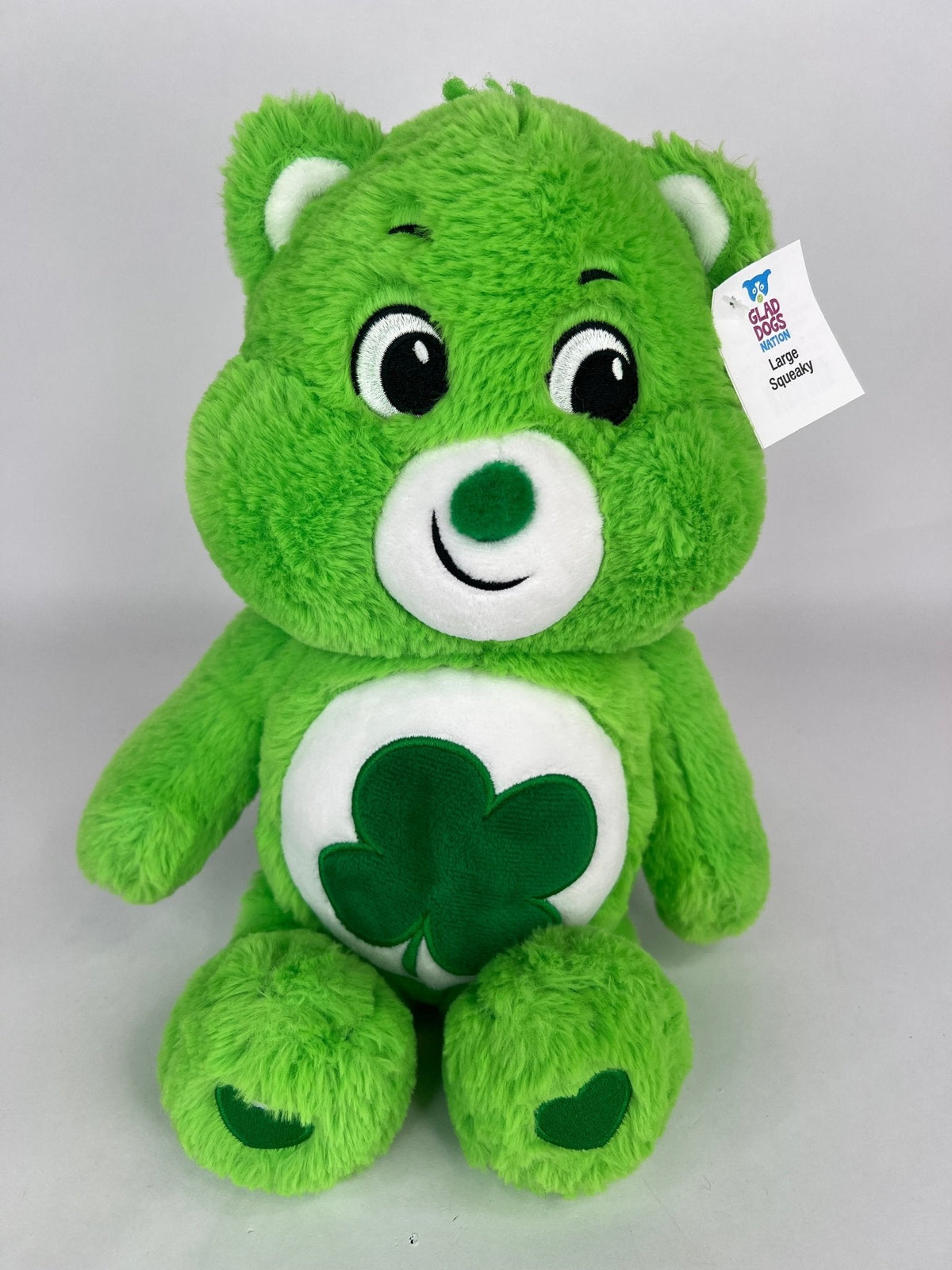 Green plush dog toy bear with clover belly applique and friendly stitched smile.