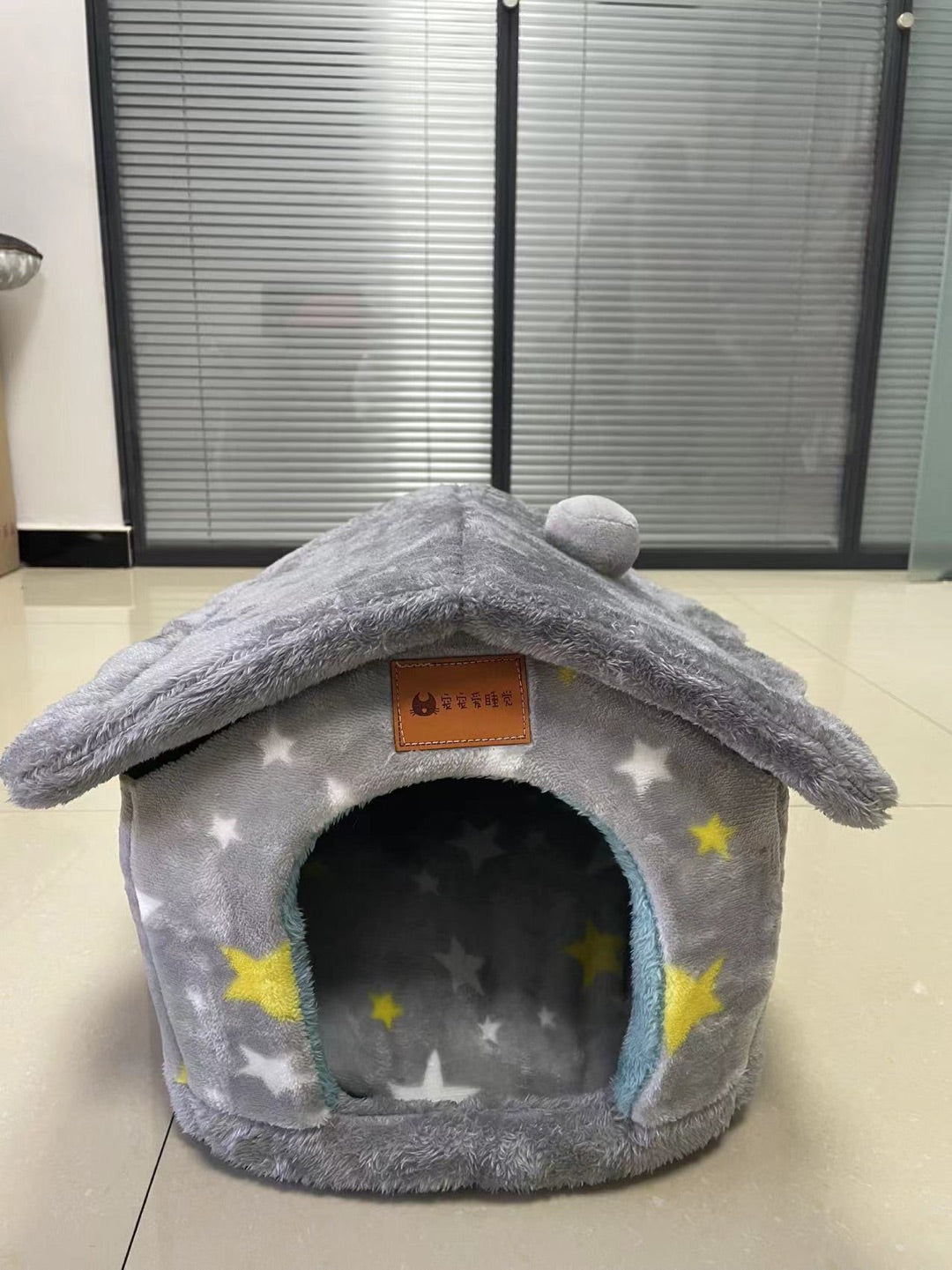 Gray plush pet house bed with star pattern and round dark doorway entrance