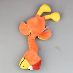 Plush bite-resistant dog toy with squeaker; orange body with yellow ends and small green accents.