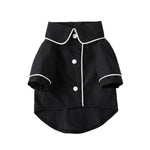 Small black pet dog jacket with white trim, snap buttons, and rolled cuff sleeves