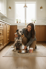 Pet probiotic powder jar with scoop in bowl, shown with a dog and handler