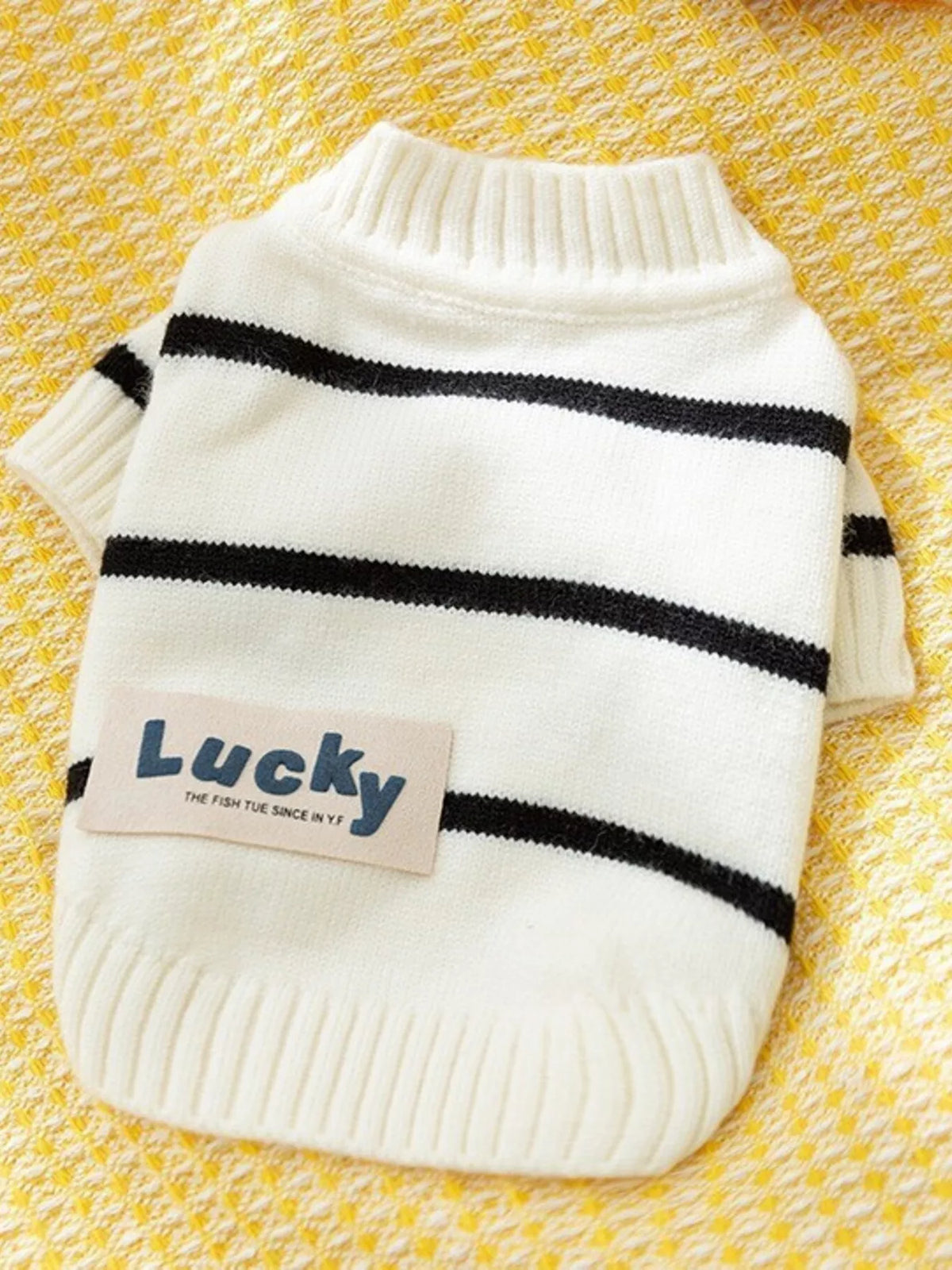 White knitted pet sweater with black horizontal stripes and blue patch text