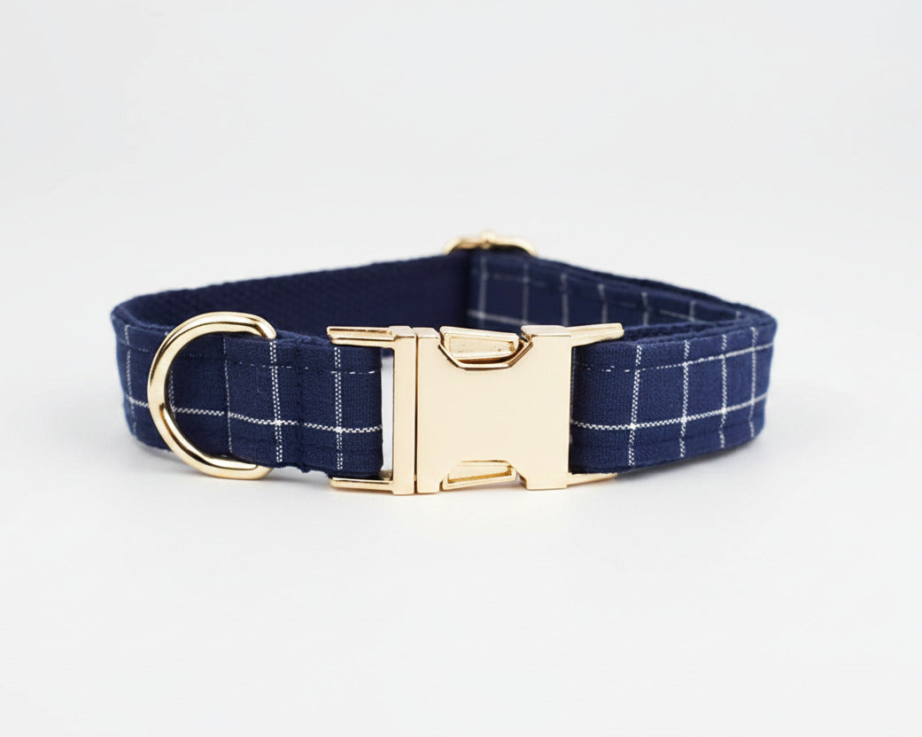 Dark blue plaid dog collar with gold buckle and D-ring, flat lay