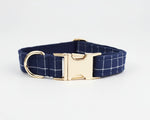 Dark blue plaid dog collar with gold buckle and D-ring, flat lay
