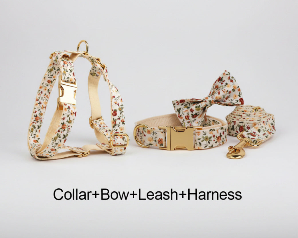 Floral dog collar, bowtie, harness, and leash set on ivory fabric with gold hardware