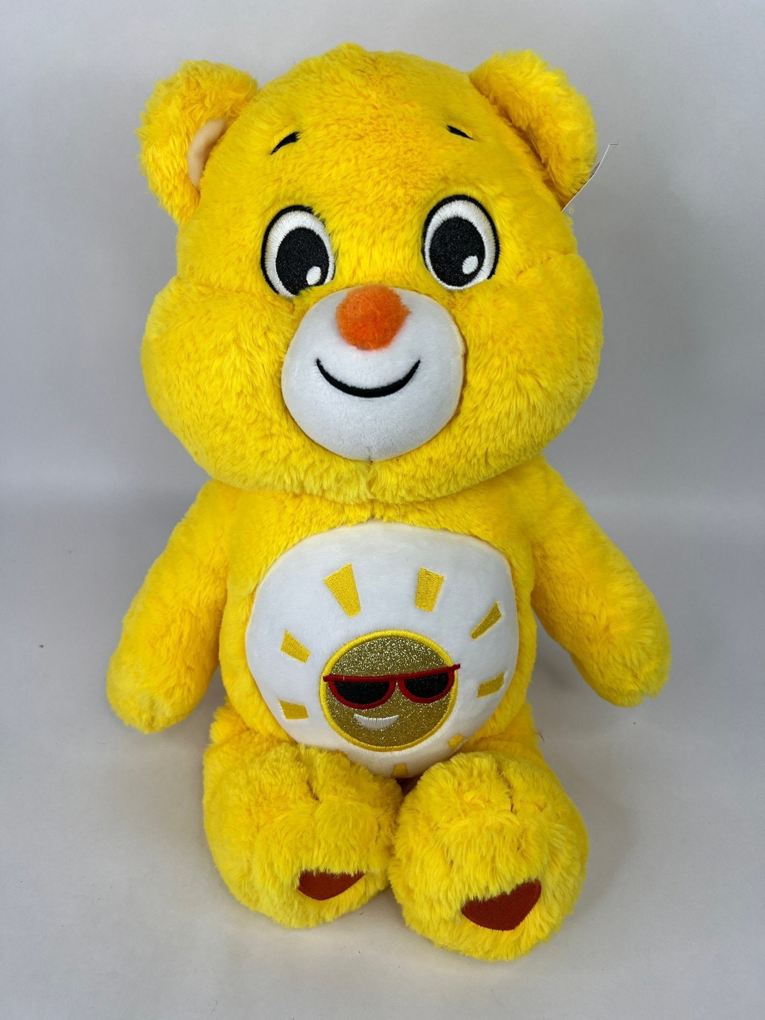 Yellow plush dog toy bear with cheerful face and sunglasses sunshine belly badge.