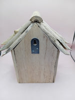 Weathered wood birdhouse with metal latch plate and pointed roof, front view