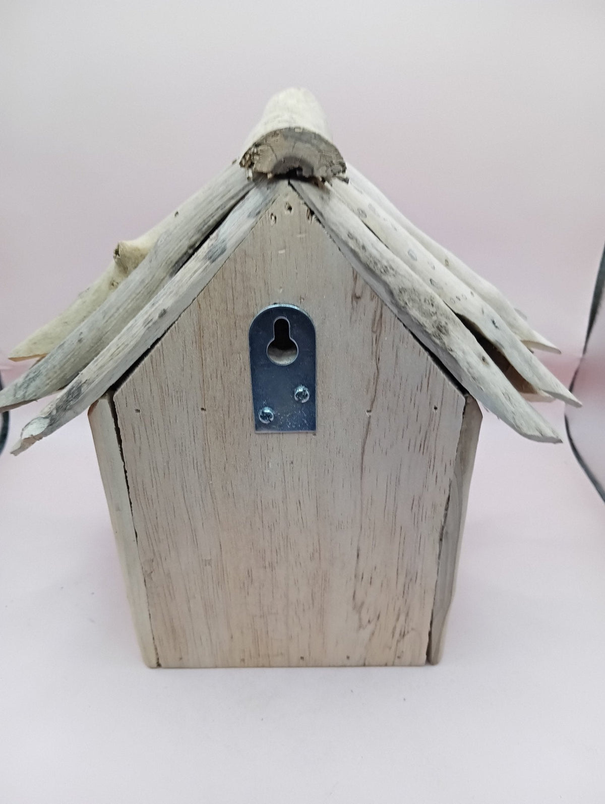 Weathered wood birdhouse with metal latch plate and pointed roof, front view