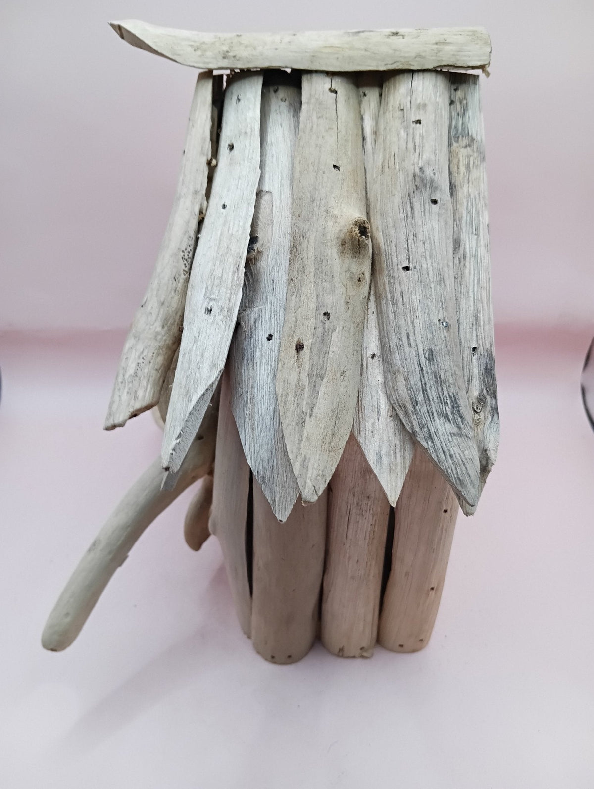 Rustic driftwood birdhouse with layered plank roof and no visible front opening