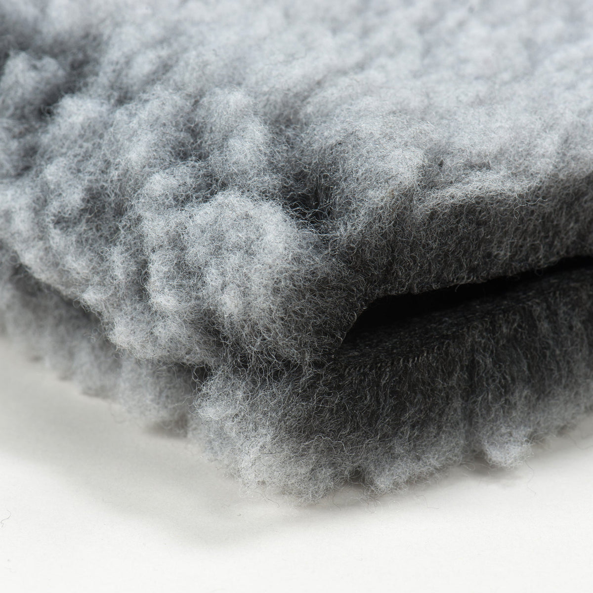 Close-up of gray fleece mat pet bed texture with soft tufted surface
