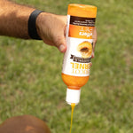 Apricot Kernel pet shampoo bottle in orange held in hand; yellow liquid drips from nozzle.