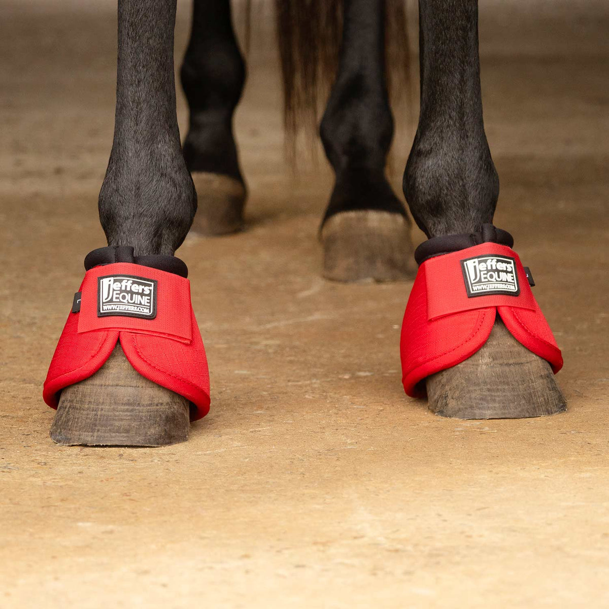 Red no-turn bell boots on horse hooves with padded cuffs and Jeffer's Equine logos.