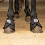 Black no-turn bell boots on horse hooves with padded cuffs and front straps