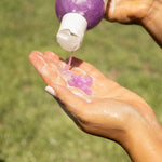 Purple shampoo gel being dispensed onto a hand from a bottle applicator.