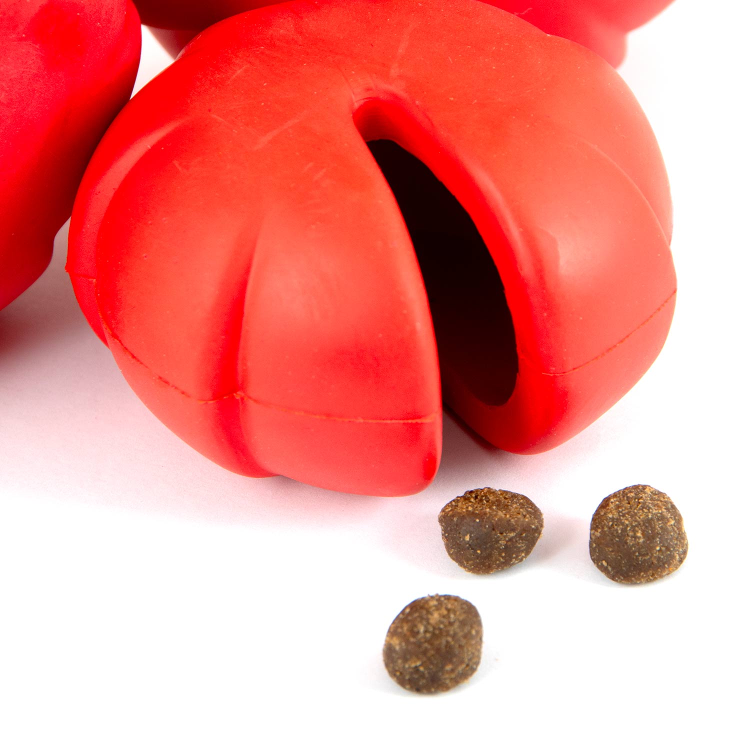Red rubber treat-dispensing chew toy close-up with oval openings and texture