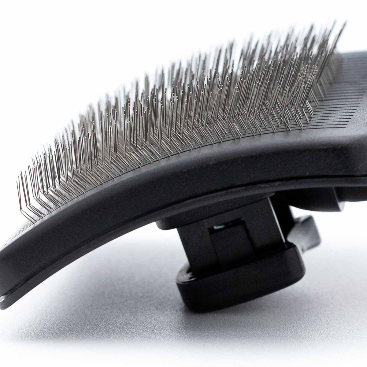 Slicker grooming brush head close-up with dense metal pins on a black base