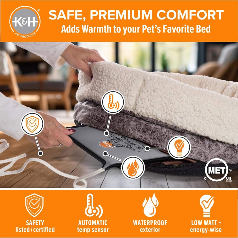 Grey heated pet pad under bed cover with power cord visible