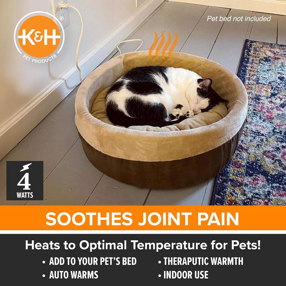 Grey heated pet pad inside round pet bed with power cord leading out