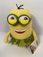 Yellow Minion plush with oversized green goggles and green ruffled collar, smiling.