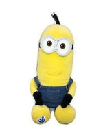 Yellow Minion plush with round goggles and blue overalls, sitting with legs crossed.