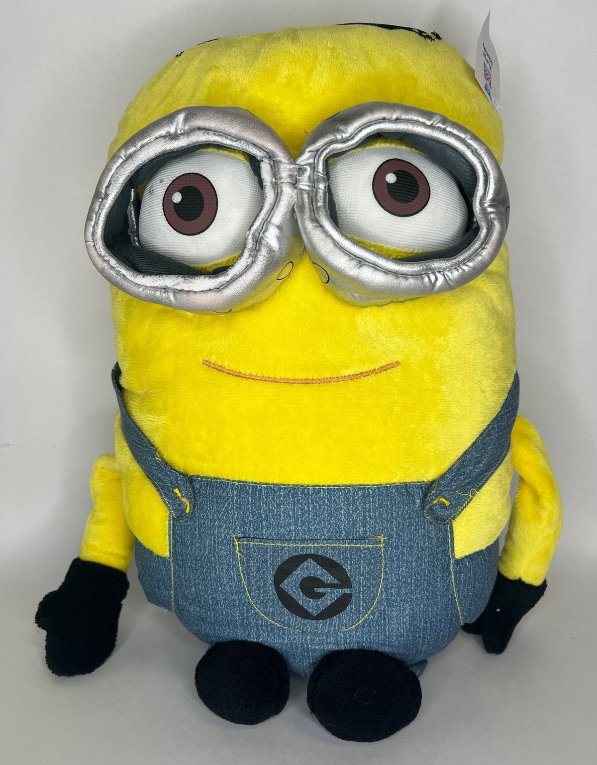 Yellow Minion plush with large silver goggles and dark overalls front panel