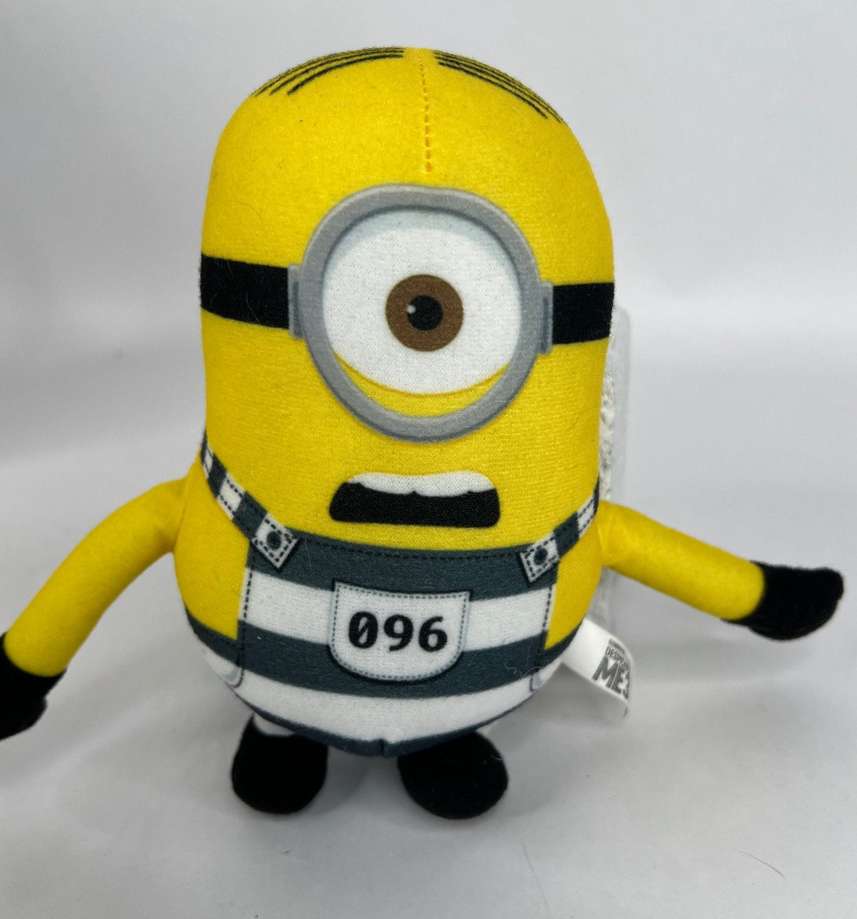 Yellow Minion plush with round gray goggles and black belt badge marked 096