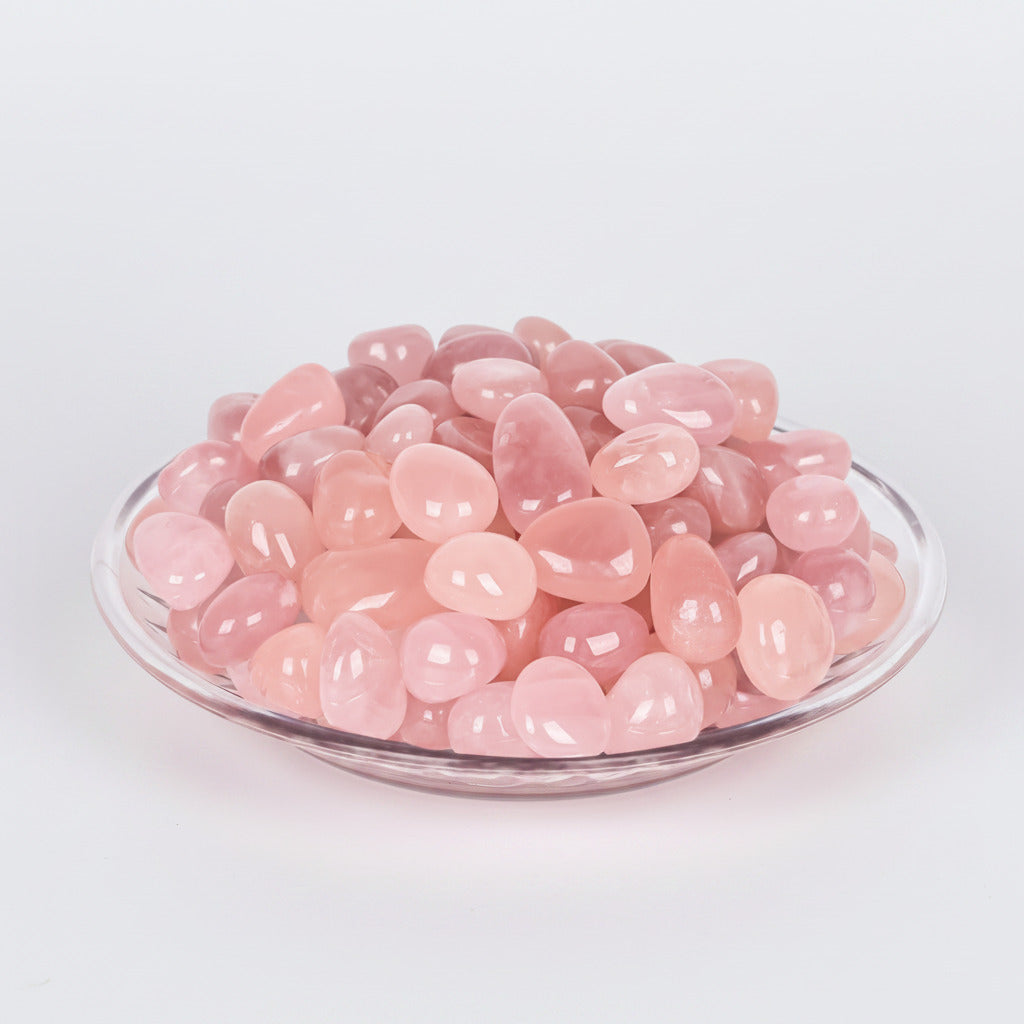 Rose quartz tumbled stones, pale pink smooth pebbles in a glass bowl