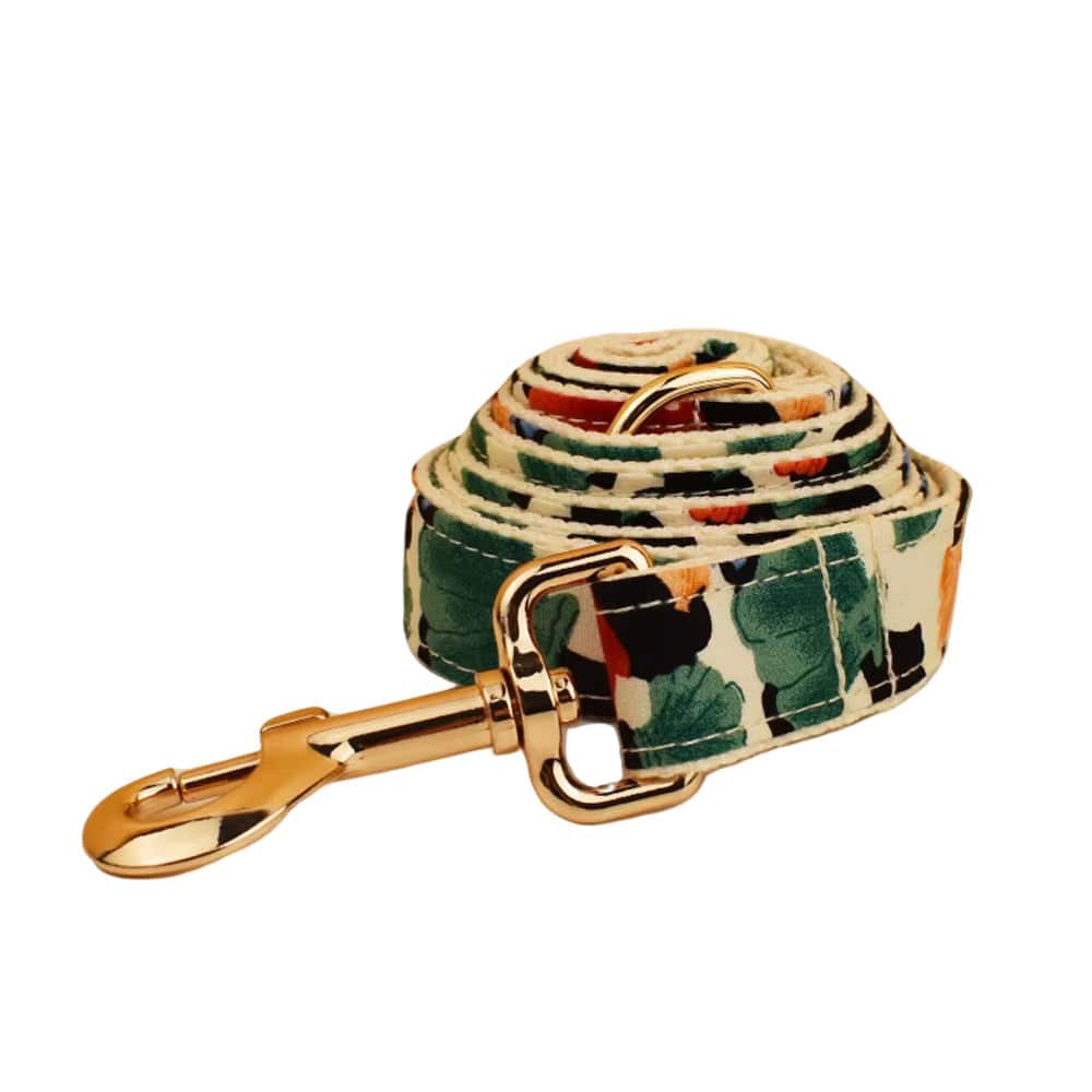 Floral pet leash with gold clasp, beige webbing with orange, green, and blue leaf prints