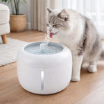 White pet water fountain with cat drinking from the bubbling top spout