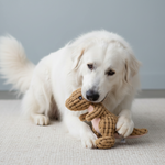 Tan animal-shaped rubber molar chew toy figure with textured body, held by a dog