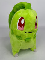 Green plush squeaky dog toy with cartoon face, rounded body and feet