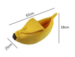 Banana-shaped pet bed in yellow plush with darker front end tip and curved raised side