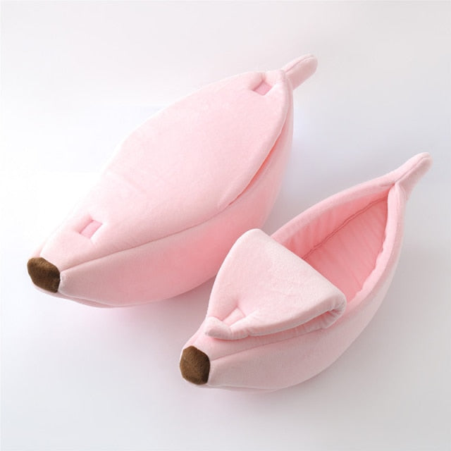 Banana-shaped pet bed in blush pink fabric with curved sides and brown end tip pads
