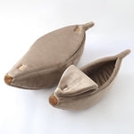 Banana-shaped pet bed in beige fabric with curved shape and darker brown end tip pads