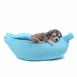 Blue banana-shaped plush pet bed with sleeping puppy inside