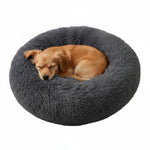 Plush donut pet bed in dark charcoal, with small dog curled inside