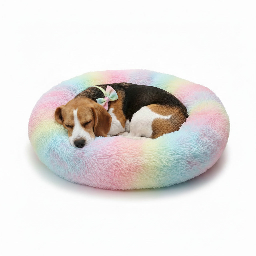 Plush donut pet bed with rainbow tie-dye pattern, with two dogs curled