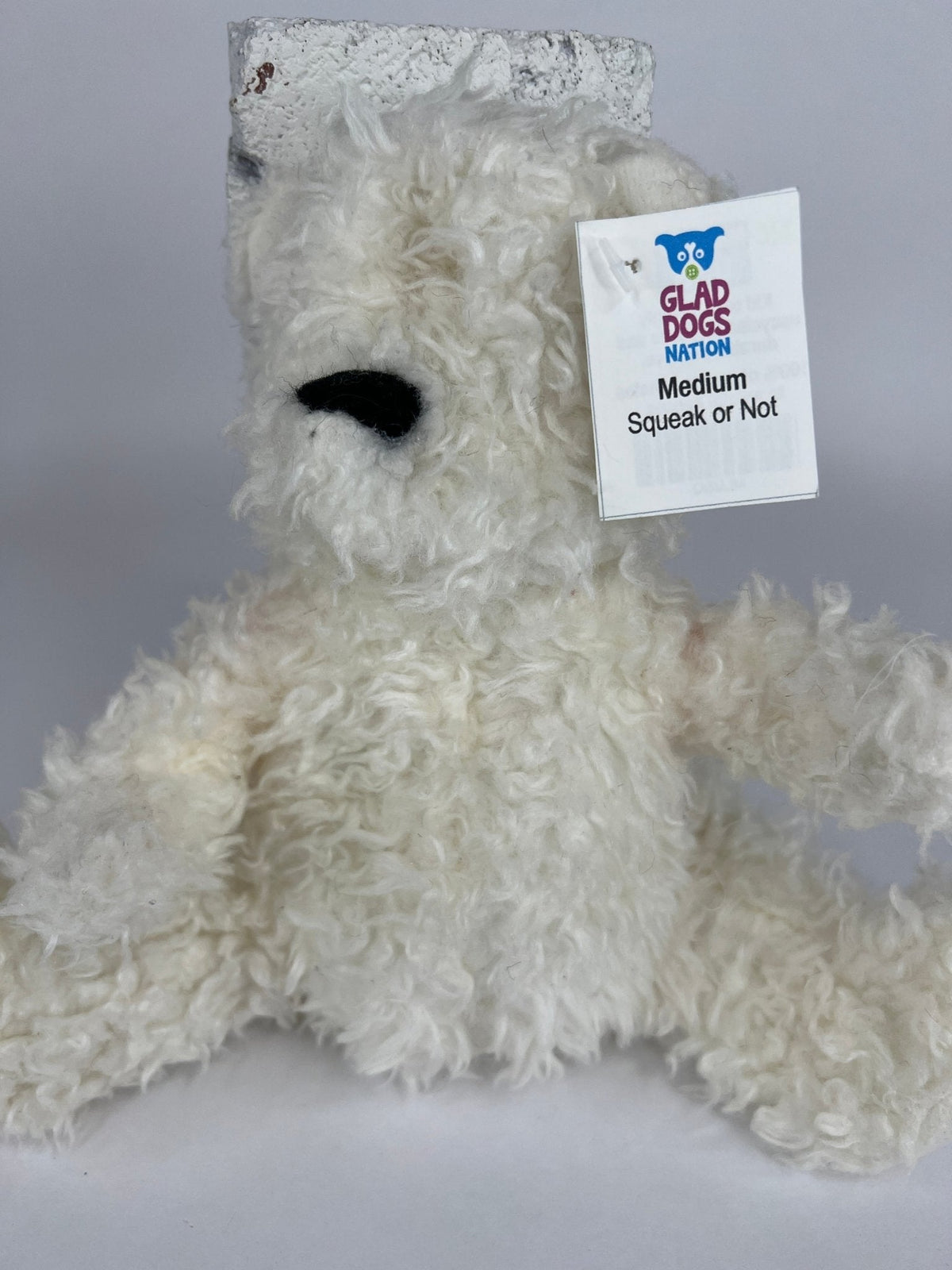 White shag plush dog toy with black nose and squeaker tag