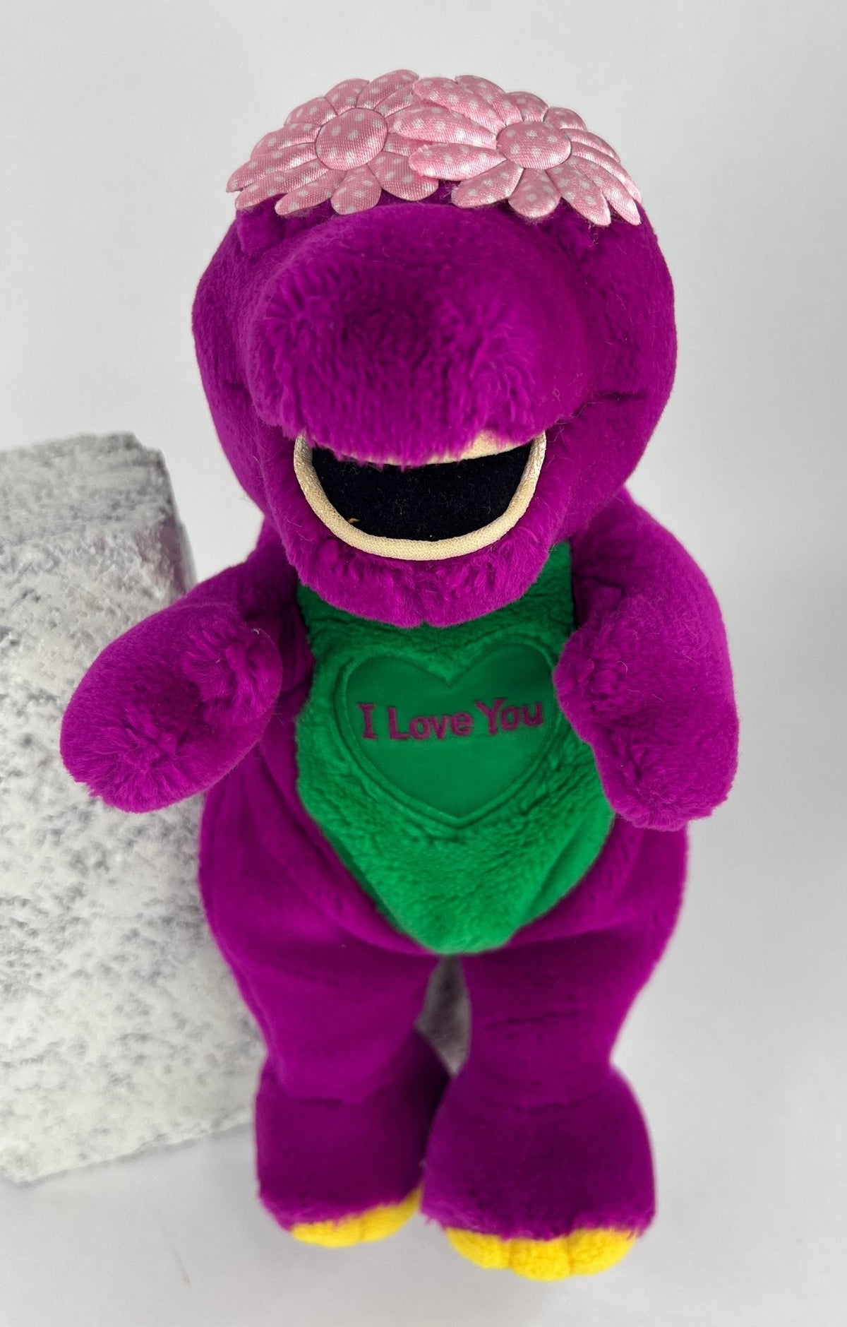 Purple plush duck toy with open mouth and green belly, squeaker tag