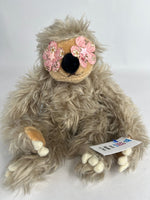 Tan shag plush dog toy with pink flower ear accents and squeaker tag