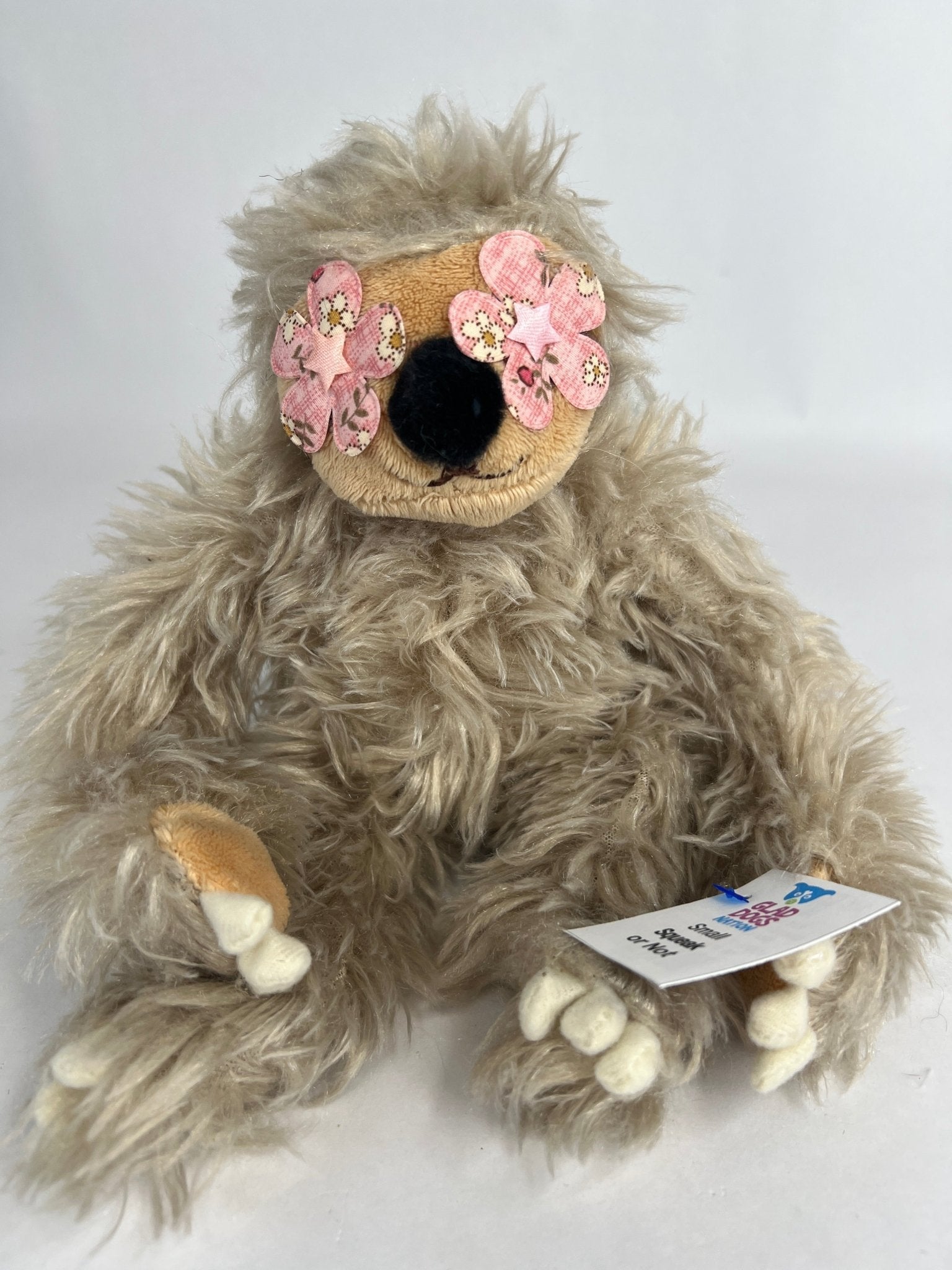 Tan shag plush dog toy with pink flower ear accents and squeaker tag