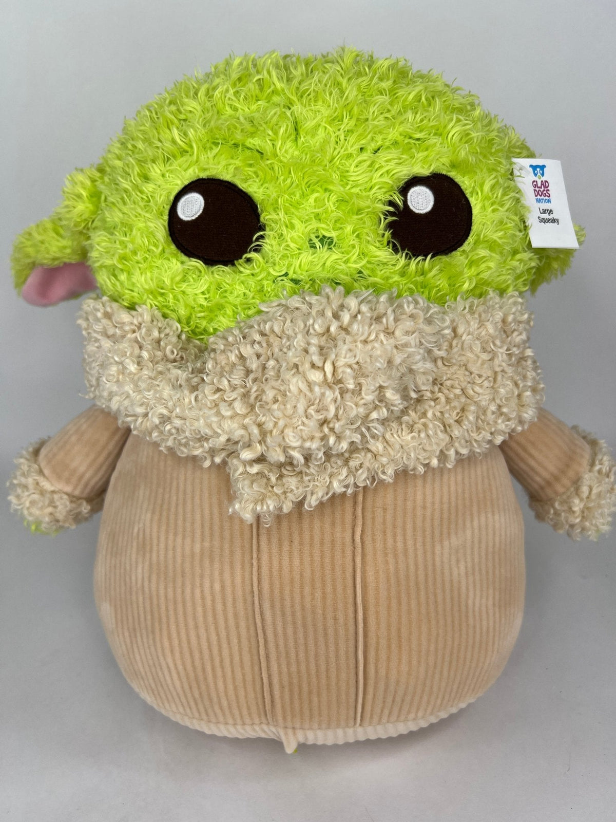 Green-and-cream plush dog toy with large black eyes and fuzzy rounded body