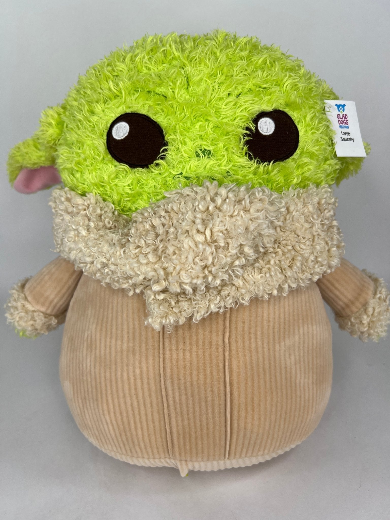 Green-and-cream plush dog toy with large black eyes and fuzzy rounded body