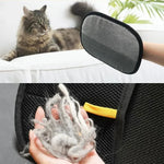 Black pet grooming mitt with gray inner pad and yellow tab, held for brushing