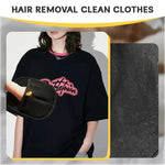 Black pet grooming hair removal glove with yellow strap, held in front of shirt